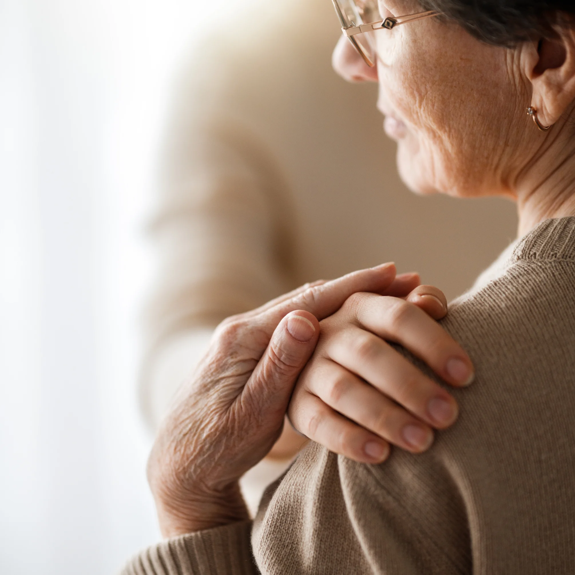 Mano di un'assistente sulla spalla di una signora anziana